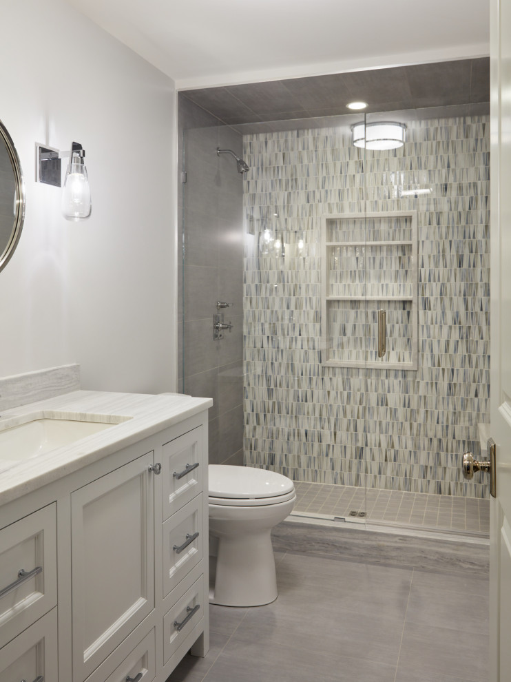 Пример оригинального дизайна: маленькая ванная комната в стиле неоклассика (современная классика) с фасадами с утопленной филенкой, серыми фасадами, раздельным унитазом, разноцветной плиткой, душевой кабиной, врезной раковиной, тумбой под одну раковину, напольной тумбой, душем в нише, стеклянной плиткой, белыми стенами, полом из керамогранита, серым полом, душем с раздвижными дверями, разноцветной столешницей и нишей для на участке и в саду