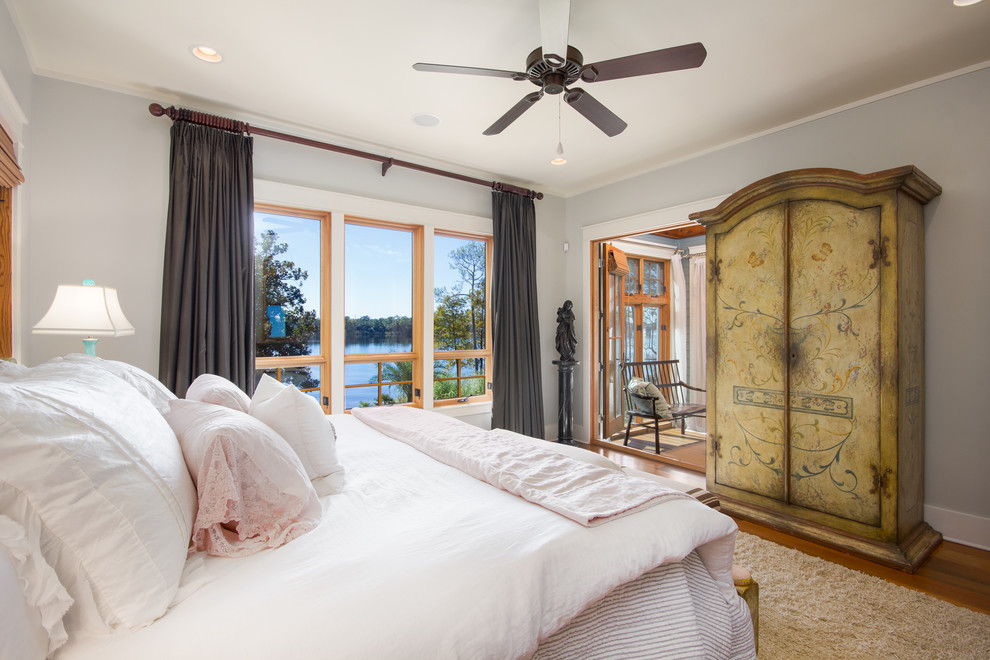 Photo of a beach style bedroom with grey walls, medium hardwood floors and brown floor.
