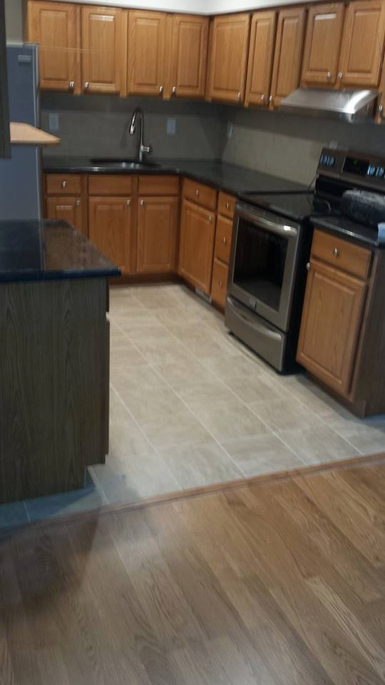 Small traditional l-shaped eat-in kitchen in Dallas with an undermount sink, raised-panel cabinets, brown cabinets, quartzite benchtops, beige splashback, porcelain splashback, stainless steel appliances, porcelain floors and black benchtop.