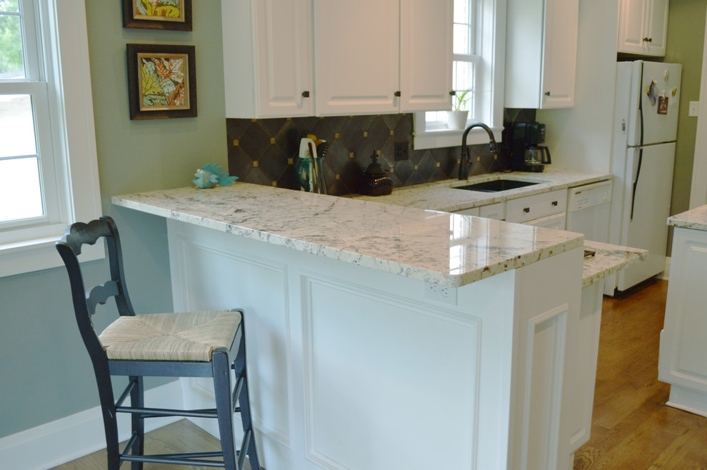 Eat-in kitchen - mid-sized transitional u-shaped light wood floor and beige floor eat-in kitchen idea with a drop-in sink, raised-panel cabinets, white cabinets, granite countertops, black backsplash, ceramic backsplash, white appliances and an island
