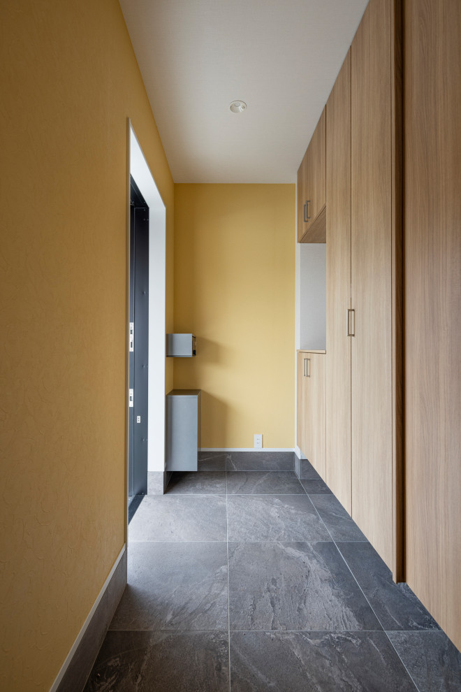 Photo of a large modern entryway in Other with yellow walls, ceramic floors, a single front door, black floor, wallpaper and wallpaper.