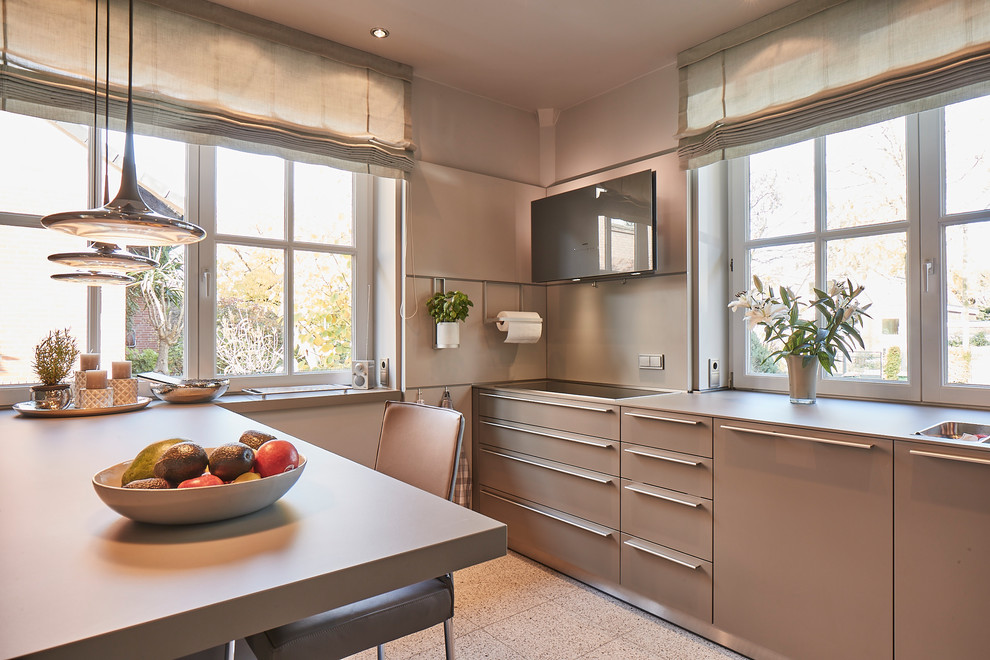 Large contemporary l-shaped open plan kitchen in Hamburg with an integrated sink, flat-panel cabinets, grey cabinets, wood benchtops, beige splashback, timber splashback, stainless steel appliances, terrazzo floors, a peninsula, beige floor and beige benchtop.