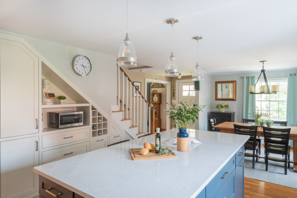 Inspiration for a large transitional l-shaped light wood floor and brown floor eat-in kitchen remodel in Boston with an undermount sink, shaker cabinets, white cabinets, quartz countertops, gray backsplash, ceramic backsplash, stainless steel appliances, an island and white countertops