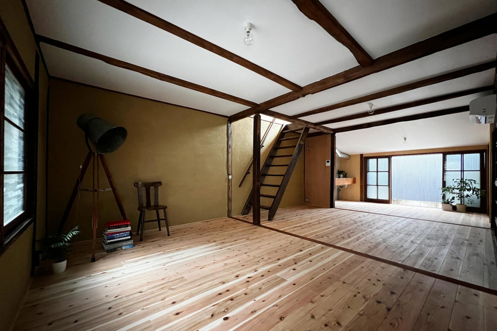 Foto di un piccolo soggiorno aperto con pareti marroni, parquet chiaro, pavimento marrone e travi a vista