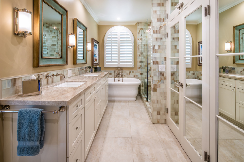 Photo of a beach style master bathroom in San Diego with recessed-panel cabinets, beige cabinets, a freestanding tub, beige tile, white tile, beige walls, an undermount sink, beige floor, an open shower, beige benchtops and an alcove shower.
