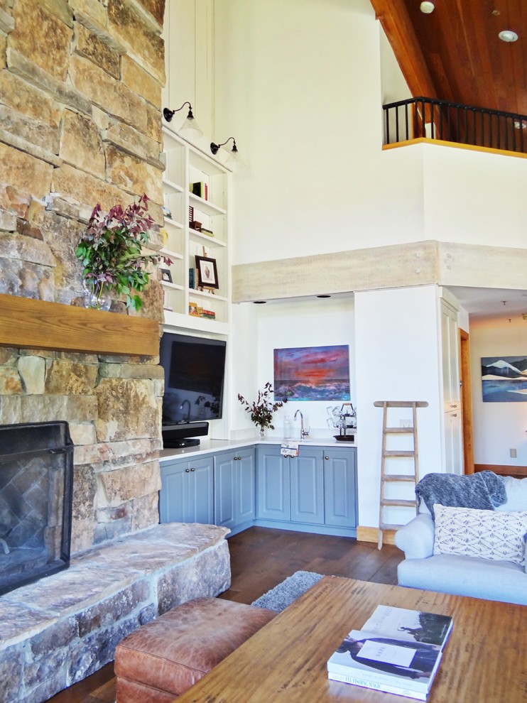 This is an example of a mid-sized country open concept living room in Salt Lake City with a home bar, white walls, medium hardwood floors, a standard fireplace, a stone fireplace surround, a built-in media wall and brown floor.