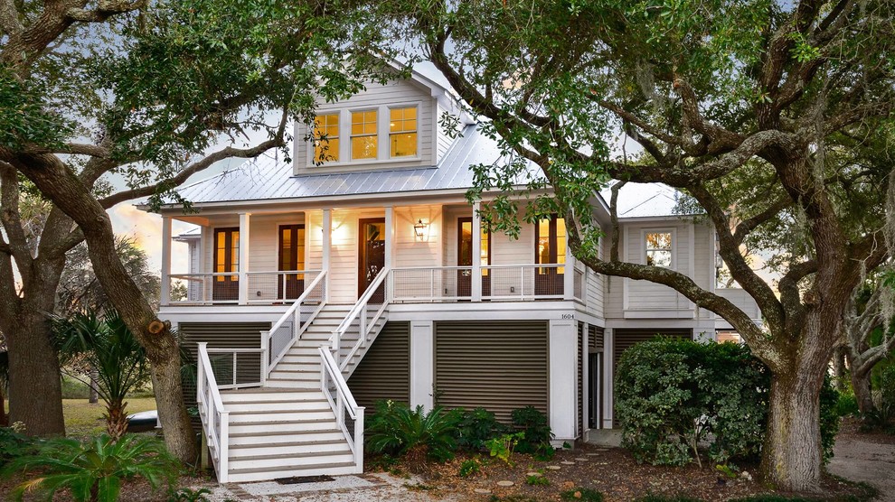 Photo of a large traditional two-storey white house exterior in Charleston with concrete fiberboard siding, a hip roof and a metal roof.
