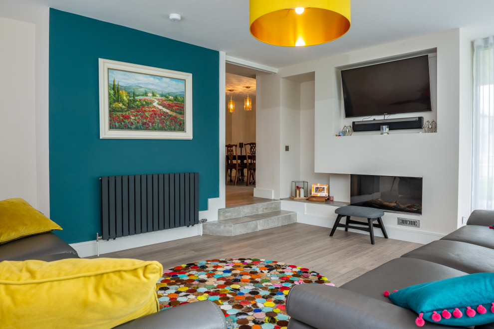 Cette image montre un salon design avec un mur vert, une cheminée double-face et un téléviseur dissimulé.
