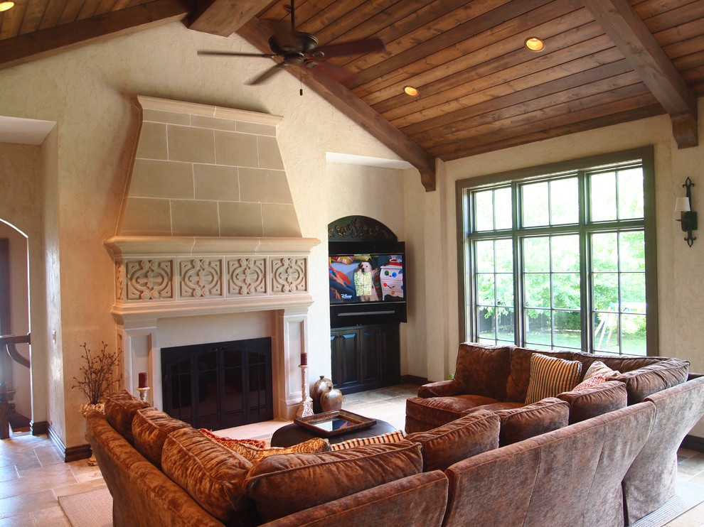 Inspiration for a large country open concept family room in St Louis with limestone floors, a standard fireplace, a stone fireplace surround, a concealed tv, a home bar, beige walls and beige floor.