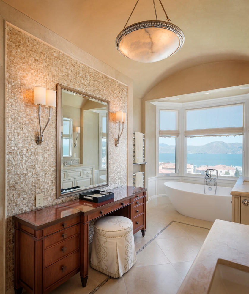 Photo of a traditional bathroom in San Francisco with dark wood cabinets, a freestanding tub, beige tile, beige walls and recessed-panel cabinets.