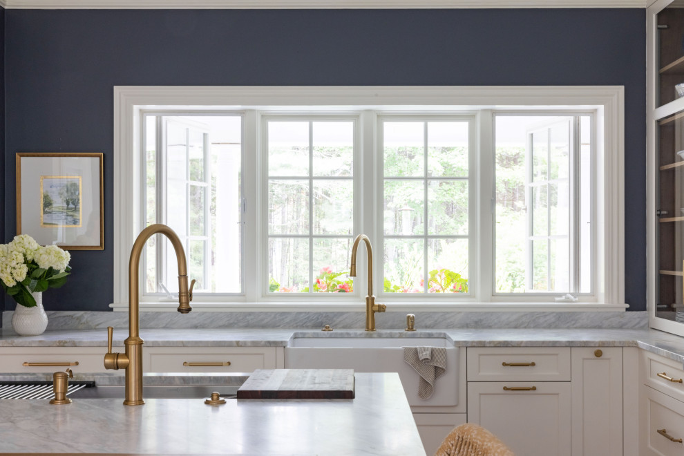 Design ideas for a mid-sized traditional l-shaped eat-in kitchen in Portland Maine with a farmhouse sink, flat-panel cabinets, white cabinets, marble benchtops, white splashback, ceramic splashback, stainless steel appliances, light hardwood floors, with island and blue benchtop.