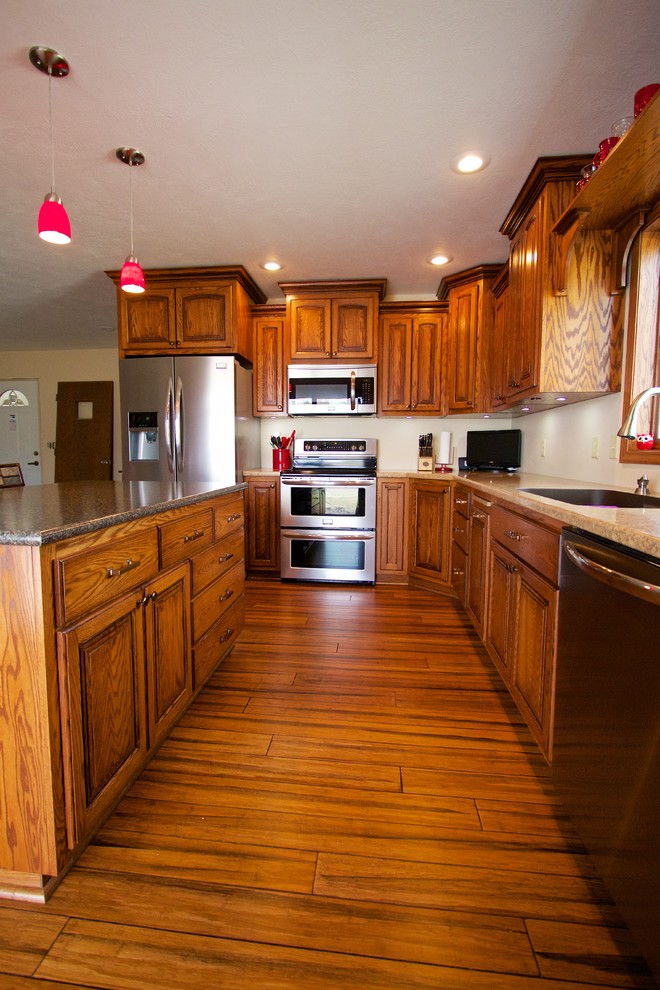 Example of a mid-sized l-shaped eat-in kitchen design with an undermount sink, medium tone wood cabinets, stainless steel appliances, an island and laminate countertops