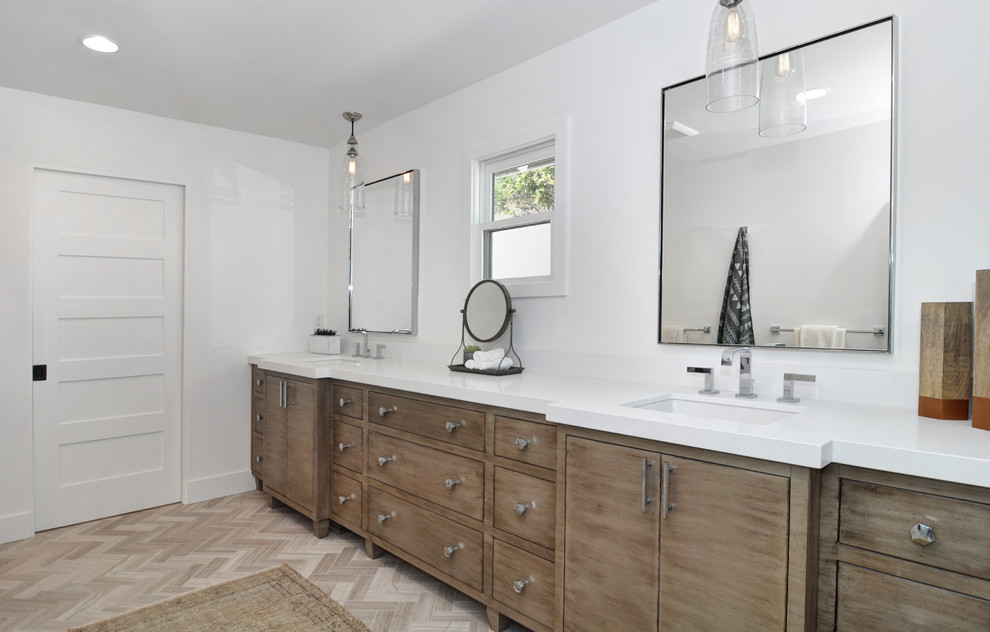 Mid-sized beach style master bathroom in Orange County with flat-panel cabinets, medium wood cabinets, an alcove shower, gray tile, white walls, light hardwood floors, an undermount sink, engineered quartz benchtops, beige floor, a hinged shower door and white benchtops.