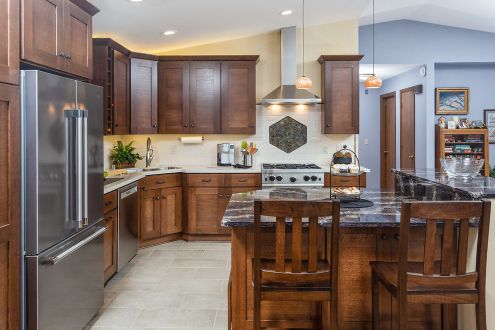 Inspiration for a mid-sized transitional l-shaped open concept kitchen remodel with recessed-panel cabinets, dark wood cabinets, quartz countertops, white backsplash, subway tile backsplash, stainless steel appliances and an island