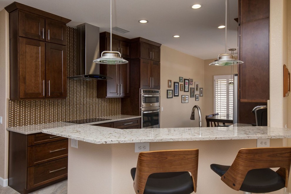 Example of a mid-sized transitional single-wall ceramic tile and gray floor eat-in kitchen design in Phoenix with shaker cabinets, dark wood cabinets, granite countertops, brown backsplash, mosaic tile backsplash, stainless steel appliances and a peninsula