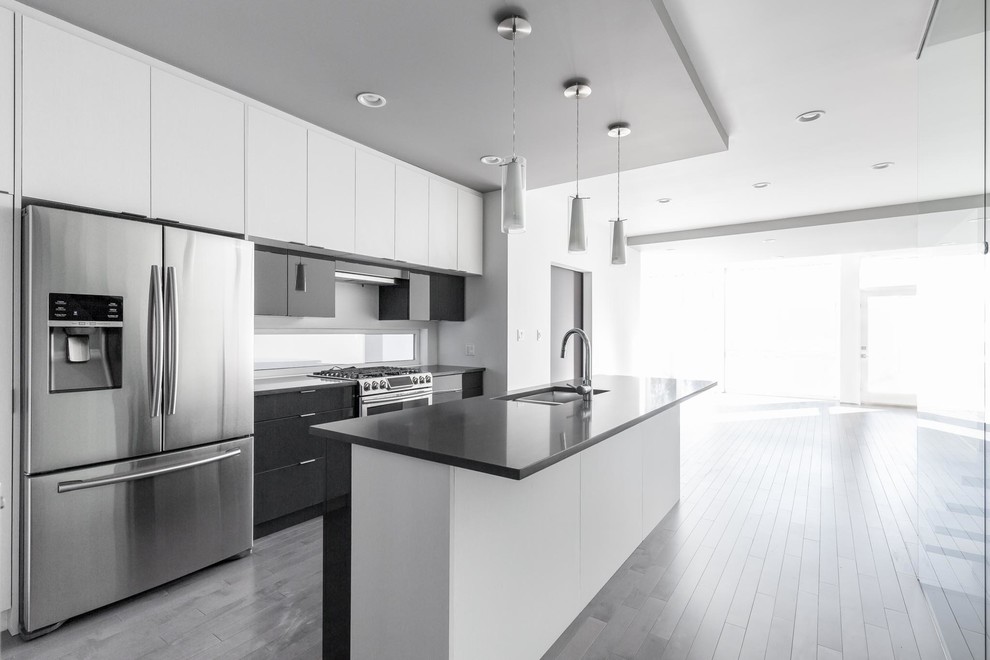 Open concept kitchen - mid-sized modern galley light wood floor and gray floor open concept kitchen idea in Edmonton with an undermount sink, flat-panel cabinets, gray cabinets, quartz countertops, window backsplash, stainless steel appliances and an island