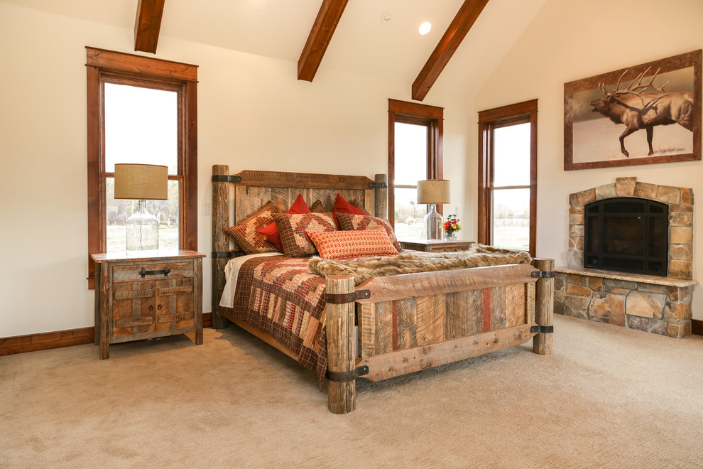 Large mountain style master carpeted and beige floor bedroom photo with beige walls, a standard fireplace and a stone fireplace