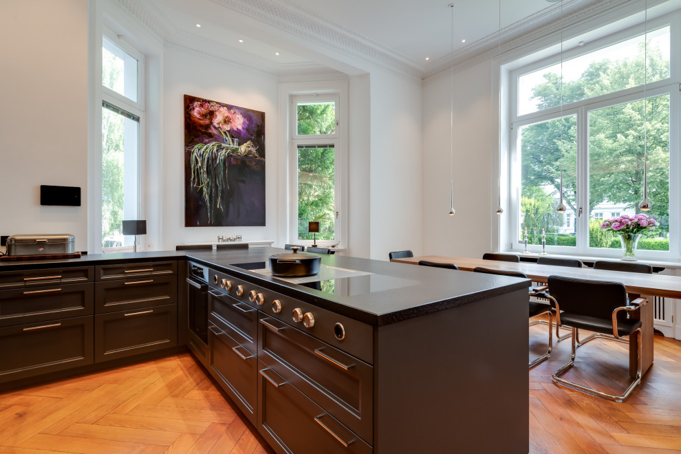 Inspiration for an expansive retro u-shaped open plan kitchen in Hamburg with a double-bowl sink, beaded cabinets, black cabinets, laminate countertops, white splashback, mirror splashback, black appliances, painted wood flooring, a breakfast bar, brown floors, black worktops and a vaulted ceiling.