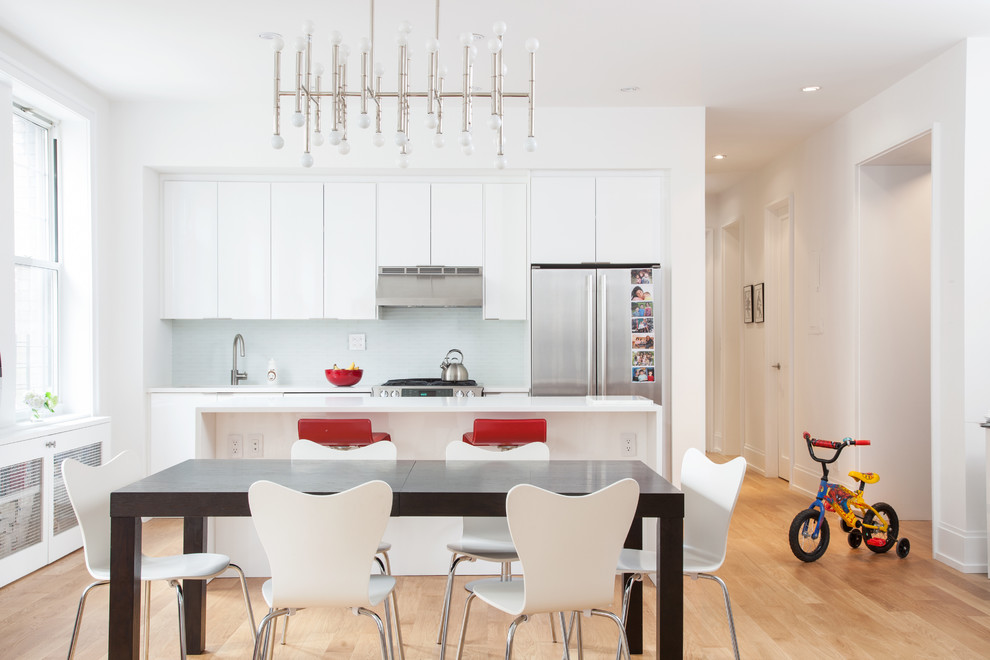 This is an example of a contemporary kitchen/dining combo in New York with white walls and medium hardwood floors.