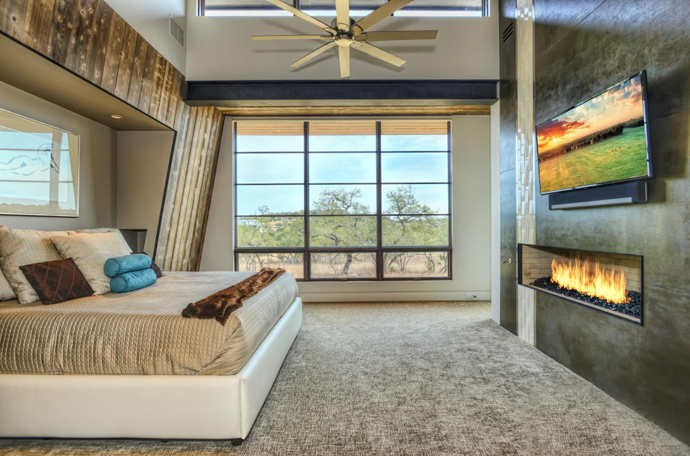 This is an example of a large modern master bedroom in Houston with grey walls, carpet, a standard fireplace, a tile fireplace surround and multi-coloured floor.