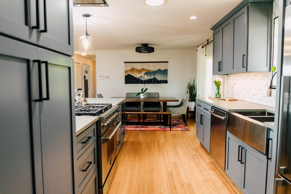 シアトルにある高級な小さなエクレクティックスタイルのおしゃれなキッチン (エプロンフロントシンク、シェーカースタイル扉のキャビネット、青いキャビネット、クオーツストーンカウンター、白いキッチンパネル、セラミックタイルのキッチンパネル、シルバーの調理設備、竹フローリング、茶色い床、グレーのキッチンカウンター) の写真