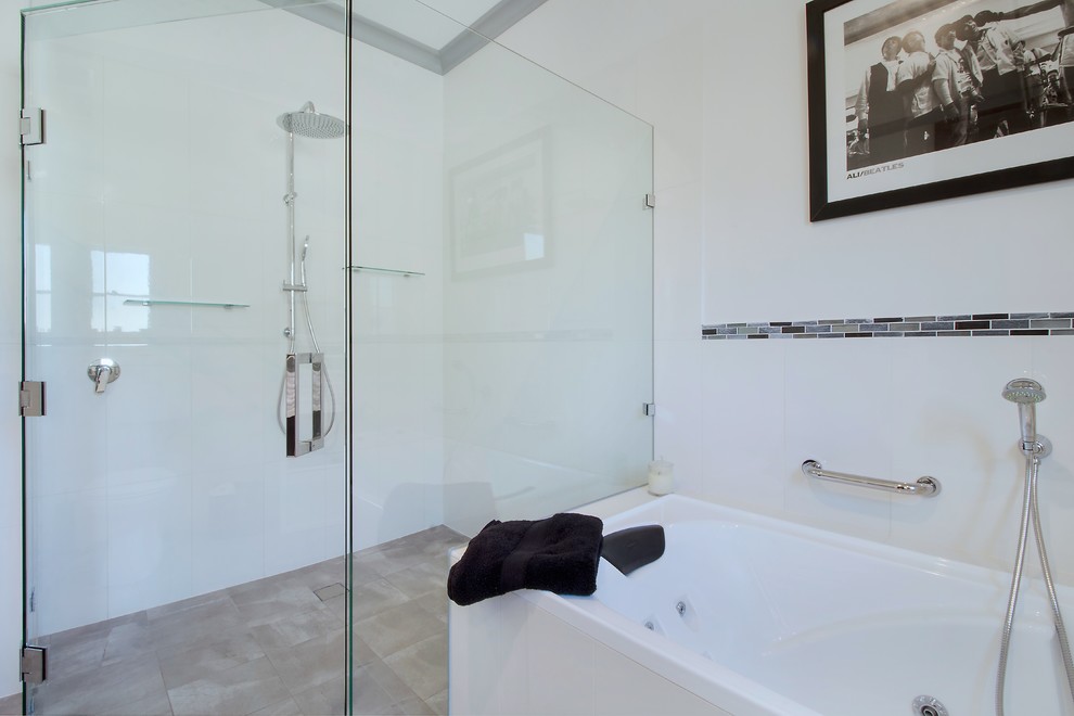 This is an example of a large modern master bathroom in Adelaide with open cabinets, white cabinets, a drop-in tub, a curbless shower, a two-piece toilet, black and white tile, ceramic tile, white walls, cement tiles, an integrated sink, laminate benchtops, grey floor, a hinged shower door and white benchtops.