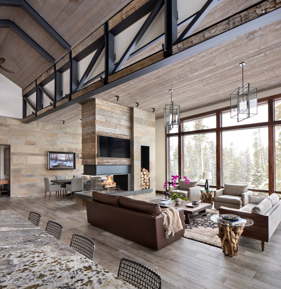 Country open concept living room in Other with dark hardwood floors, a two-sided fireplace, a stone fireplace surround and exposed beam.