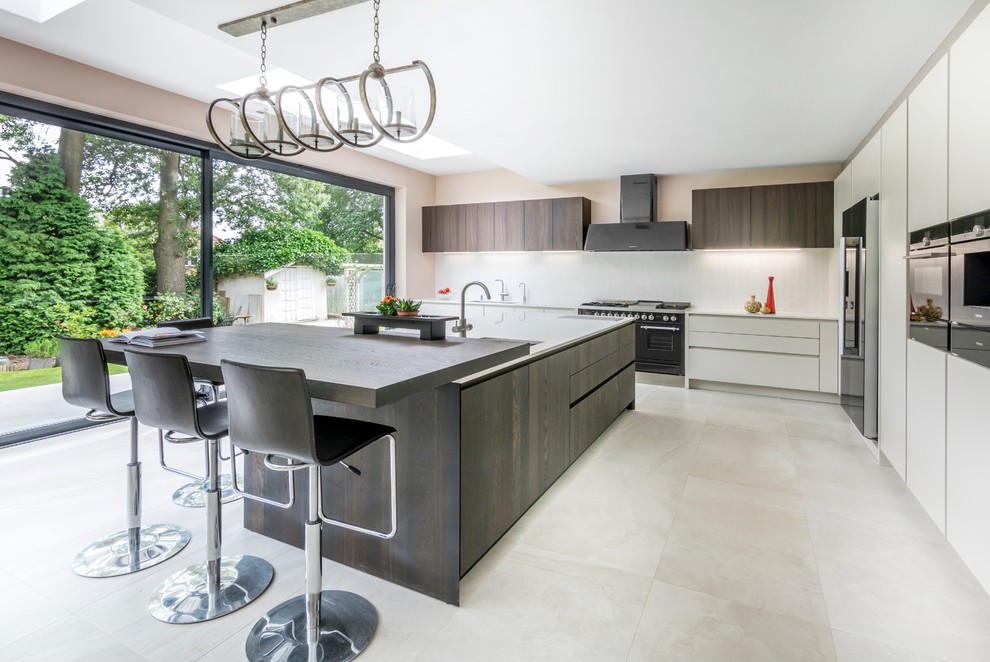 Photo of a contemporary l-shaped kitchen in London with an undermount sink, flat-panel cabinets, dark wood cabinets, white splashback, black appliances and with island.