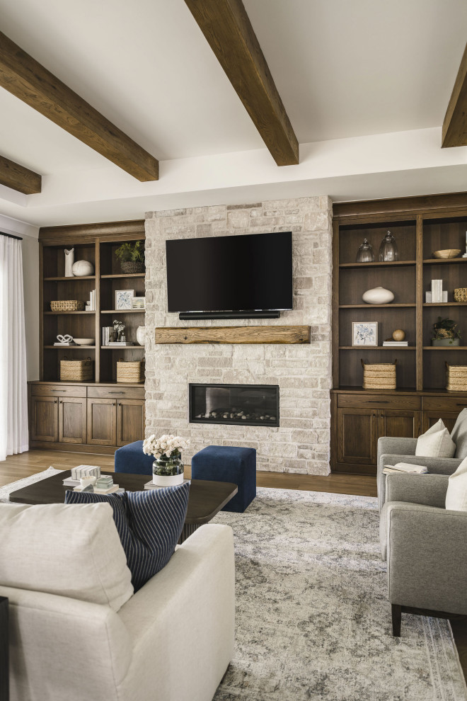 Ejemplo de sala de estar abierta tradicional renovada de tamaño medio con paredes beige, suelo de madera en tonos medios, todas las chimeneas, marco de chimenea de piedra, televisor colgado en la pared y vigas vistas