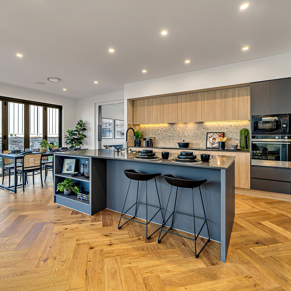 Inspiration for a mid-sized contemporary galley eat-in kitchen in Canberra - Queanbeyan with brown cabinets, quartz benchtops, beige splashback, mosaic tile splashback, black appliances, medium hardwood floors, with island and black benchtop.