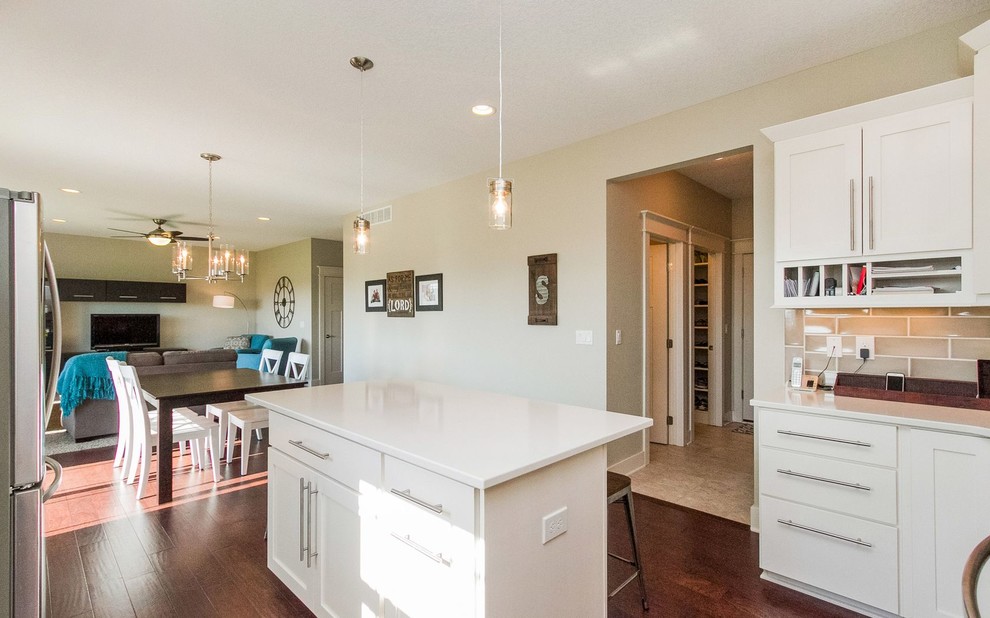 Example of a transitional u-shaped dark wood floor and brown floor eat-in kitchen design with an undermount sink, shaker cabinets, white cabinets, quartz countertops, gray backsplash, ceramic backsplash, stainless steel appliances, an island and white countertops