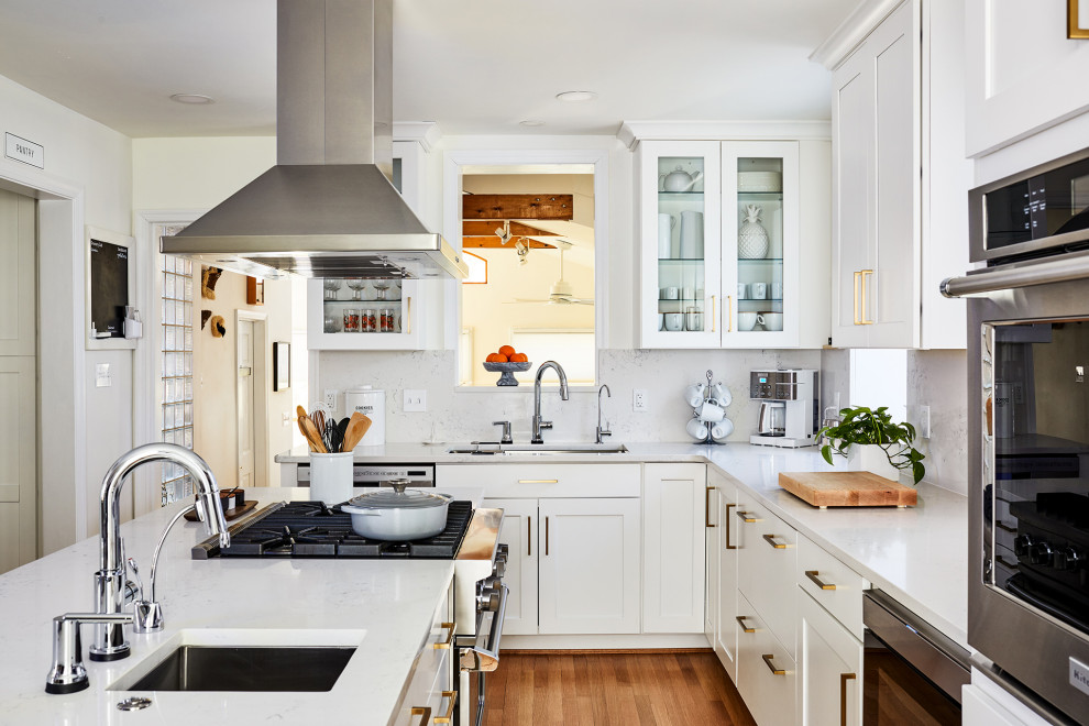 Immagine di una cucina classica di medie dimensioni con ante bianche, paraspruzzi bianco, elettrodomestici in acciaio inossidabile, pavimento in legno massello medio e top bianco