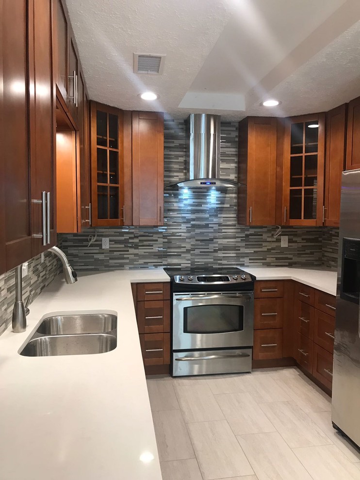 Example of a mid-sized transitional u-shaped porcelain tile and gray floor enclosed kitchen design in Houston with an undermount sink, shaker cabinets, medium tone wood cabinets, quartz countertops, multicolored backsplash, glass tile backsplash, stainless steel appliances, no island and white countertops