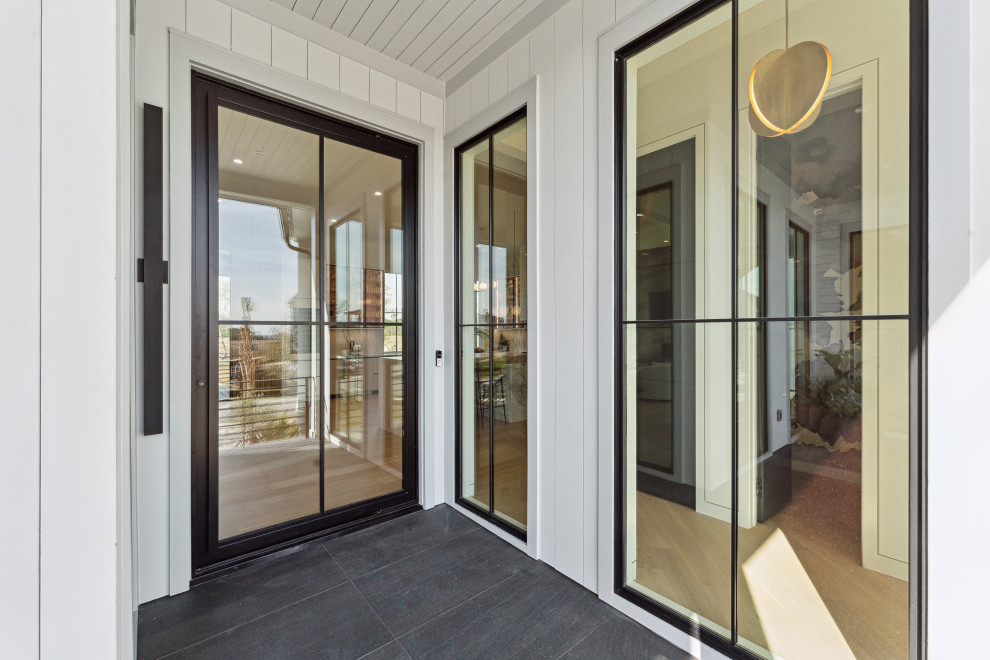 Große Moderne Haustür mit weißer Wandfarbe, Porzellan-Bodenfliesen, Drehtür, schwarzer Haustür, schwarzem Boden, Holzdielendecke und Holzdielenwänden in Charleston