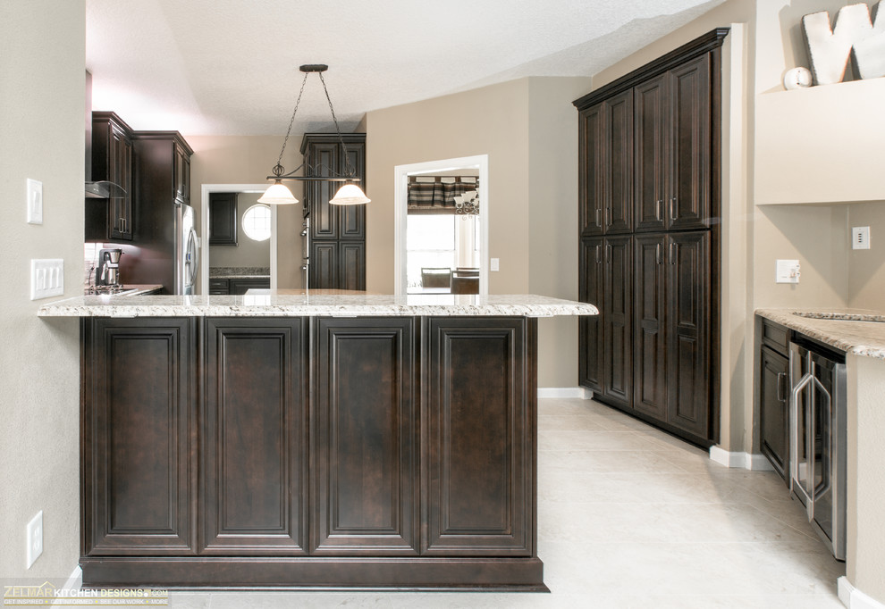 This is an example of a mid-sized transitional u-shaped eat-in kitchen in Orlando with an undermount sink, raised-panel cabinets, dark wood cabinets, granite benchtops and with island.