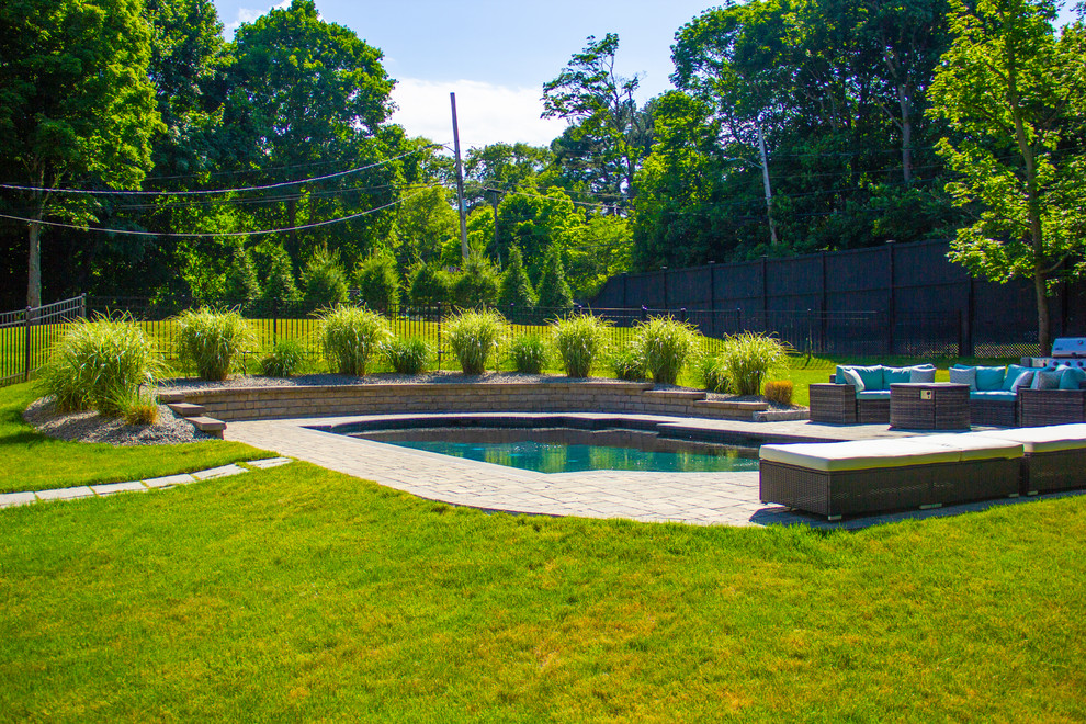 This is an example of a mid-sized country side yard custom-shaped natural pool in Boston with natural stone pavers.