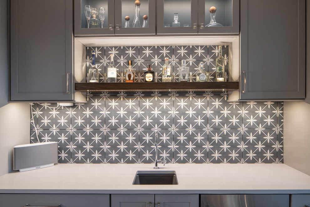 Inspiration for a mid-sized transitional single-wall wet bar in Indianapolis with an undermount sink, shaker cabinets, grey cabinets, grey splashback, cement tile splashback, medium hardwood floors, brown floor and white benchtop.