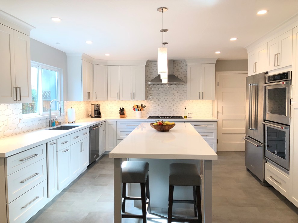 Inspiration for a contemporary u-shaped kitchen in San Francisco with an undermount sink, shaker cabinets, white cabinets, white splashback, ceramic splashback, stainless steel appliances, porcelain floors, with island and grey floor.