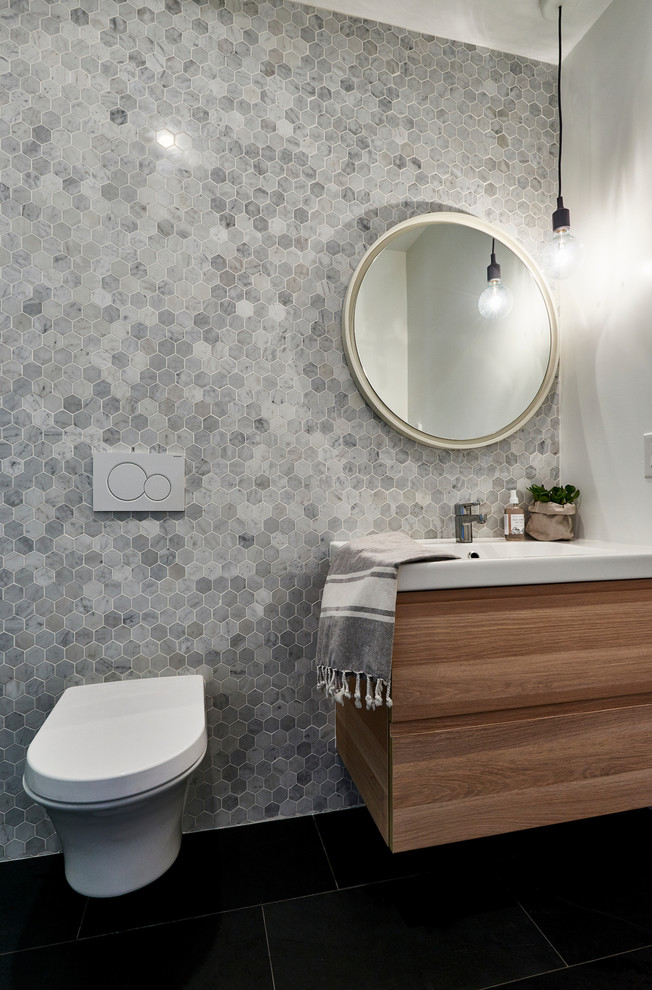 Photo of a small scandinavian kids bathroom in Toronto with flat-panel cabinets, light wood cabinets, a wall-mount toilet, gray tile, mosaic tile, white walls and slate floors.