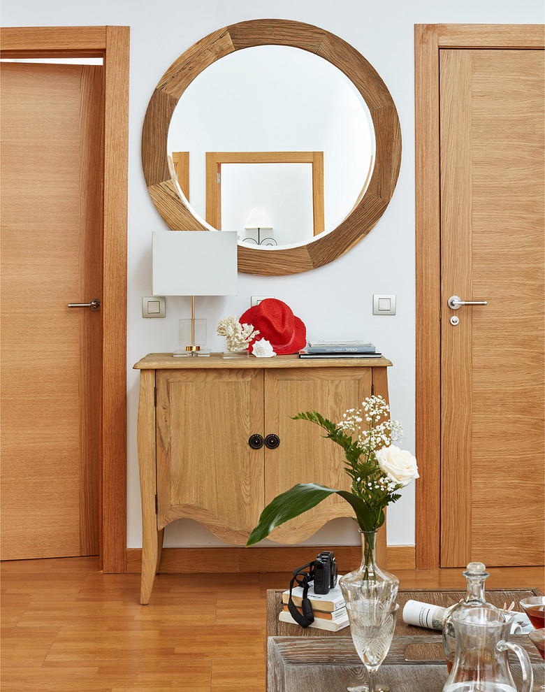 Foto de distribuidor tradicional renovado de tamaño medio con paredes blancas, suelo de madera en tonos medios, puerta simple y puerta de madera en tonos medios