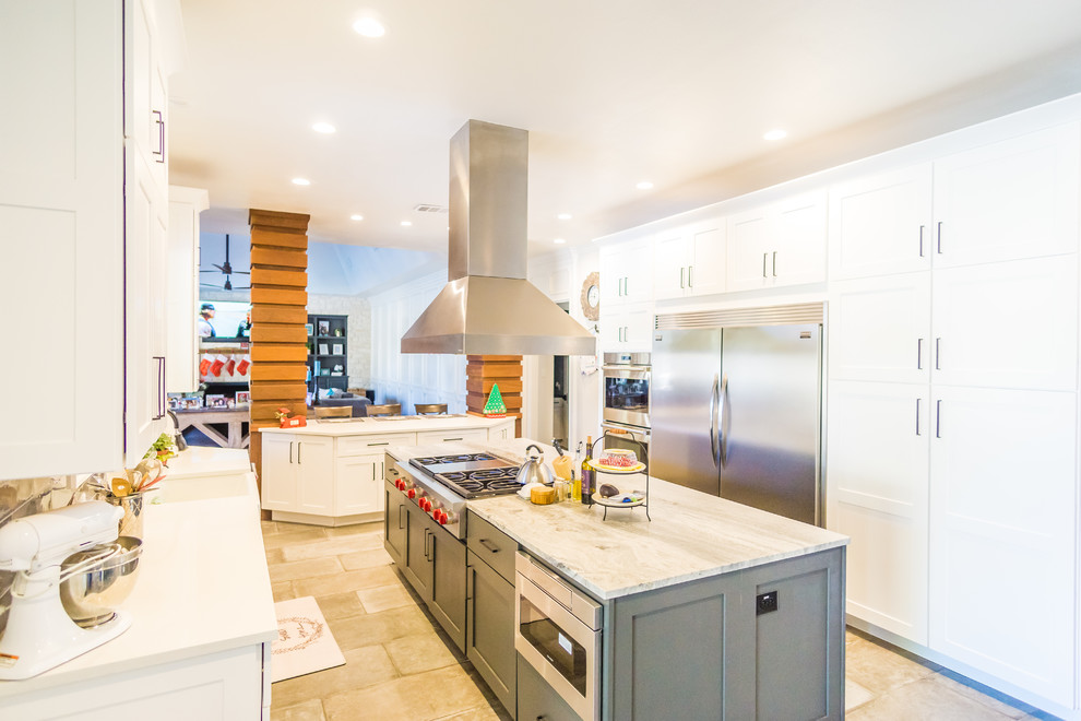 Photo of a large country galley eat-in kitchen in Austin with a farmhouse sink, shaker cabinets, white cabinets, granite benchtops, grey splashback, glass tile splashback, stainless steel appliances, cement tiles, multiple islands and grey floor.