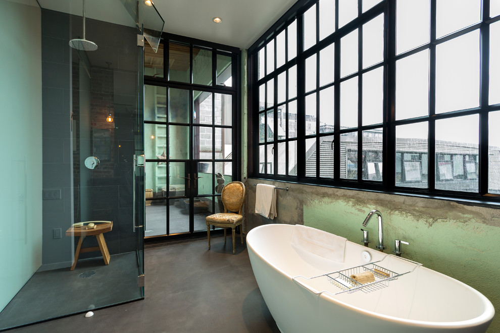 Industrial bathroom in Seattle with a freestanding tub, a corner shower, black tile, a one-piece toilet, porcelain tile, green walls, concrete floors and an undermount sink.
