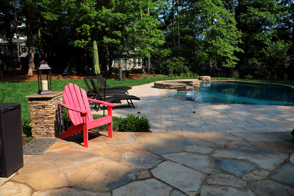 Large mountain style backyard concrete paver and custom-shaped natural hot tub photo in Raleigh