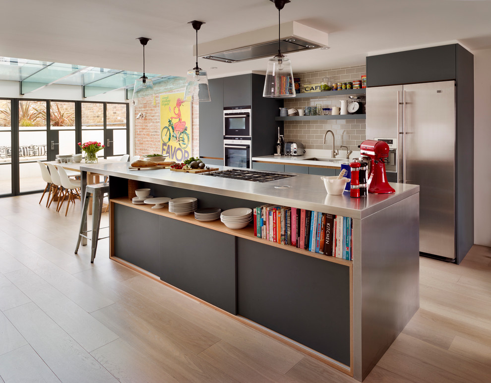 Inspiration for a large contemporary open plan kitchen in London with an undermount sink, flat-panel cabinets, grey cabinets, stainless steel benchtops, grey splashback, ceramic splashback, stainless steel appliances, light hardwood floors and with island.