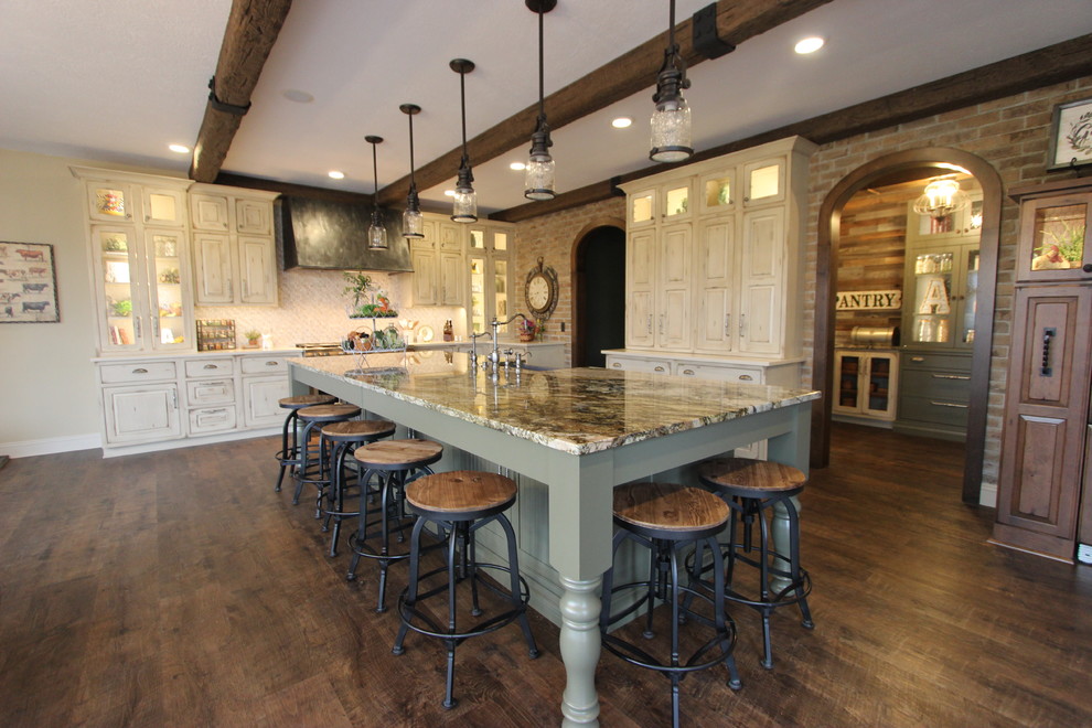 Photo of a large country l-shaped open plan kitchen in Cleveland with a farmhouse sink, raised-panel cabinets, distressed cabinets, quartzite benchtops, grey splashback, mosaic tile splashback, panelled appliances, dark hardwood floors, with island, brown floor and white benchtop.