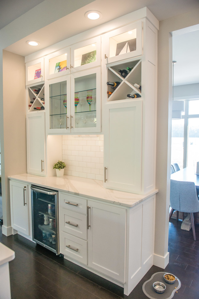 Example of a huge transitional l-shaped dark wood floor and brown floor open concept kitchen design in Chicago with a double-bowl sink, shaker cabinets, white cabinets, quartz countertops, white backsplash, ceramic backsplash, stainless steel appliances and an island