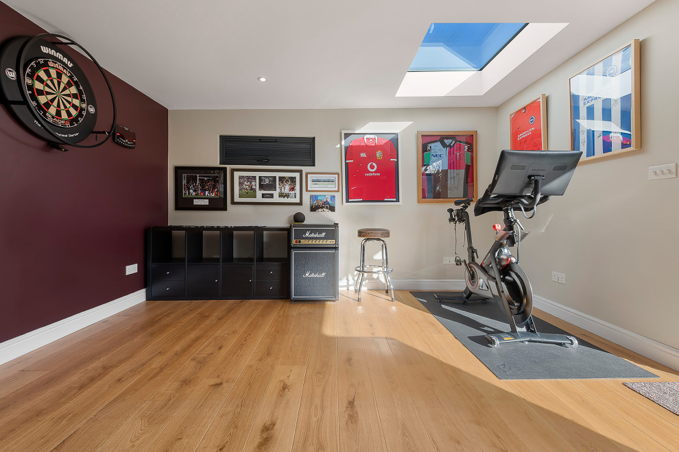 This is an example of a large contemporary home gym in Surrey with purple walls, light hardwood floors and brown floor.