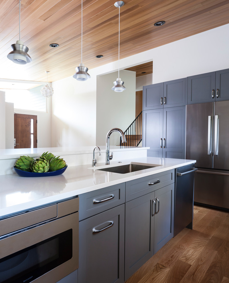 Inspiration for a mid-sized midcentury l-shaped open plan kitchen in Seattle with recessed-panel cabinets, grey cabinets, quartz benchtops, white splashback, ceramic splashback and with island.