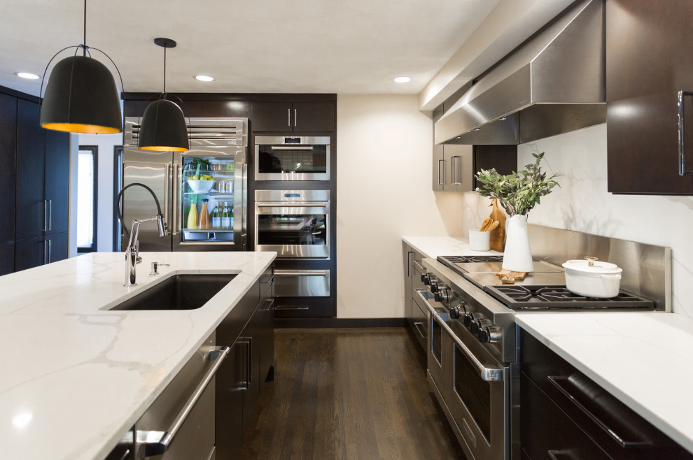Photo of a large contemporary l-shaped eat-in kitchen in Boston with an undermount sink, flat-panel cabinets, black cabinets, solid surface benchtops, white splashback, stone slab splashback, stainless steel appliances, dark hardwood floors, with island, brown floor and white benchtop.