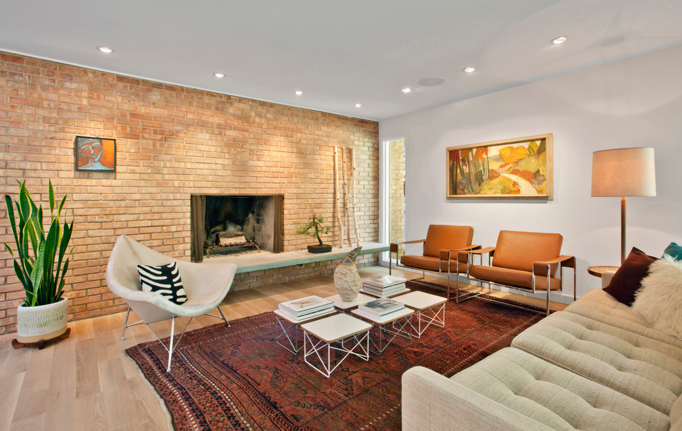 Inspiration for a mid-sized midcentury open concept living room in Indianapolis with white walls, light hardwood floors, a standard fireplace, a brick fireplace surround and beige floor.